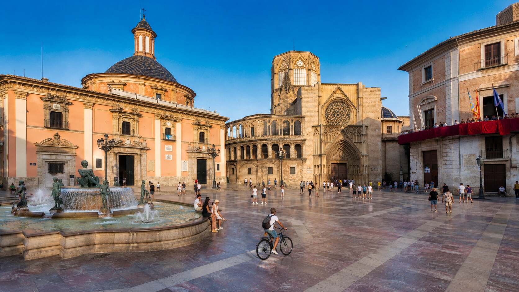 Cyclist riding across Plaça de la Mare de Déu in front of Valencia Cathedral during a Bikademy route